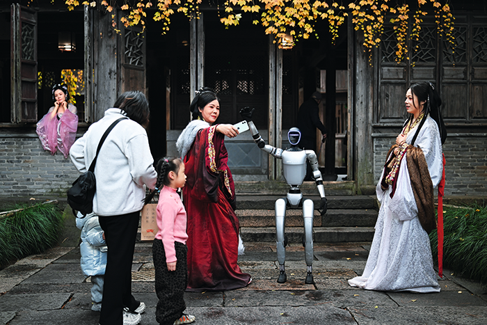 2024年12月13日，在乌镇，拍摄汉服写真的游客与“宇树科技”机器人互动留影。田建明-摄.png