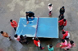 上体育课前，李祖清将乒乓球案上的雨水擦掉。