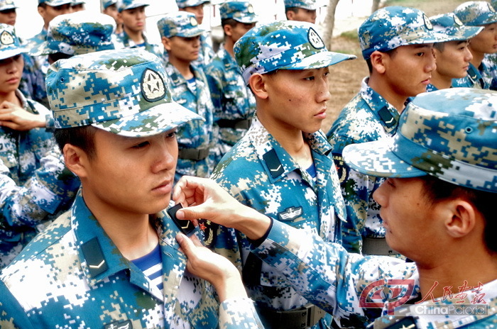 11月23日，在新兵授衔仪式上，新训干部为宋聪圣佩戴军衔、胸标、臂章等军兵种标志 。 摄影 左庚信