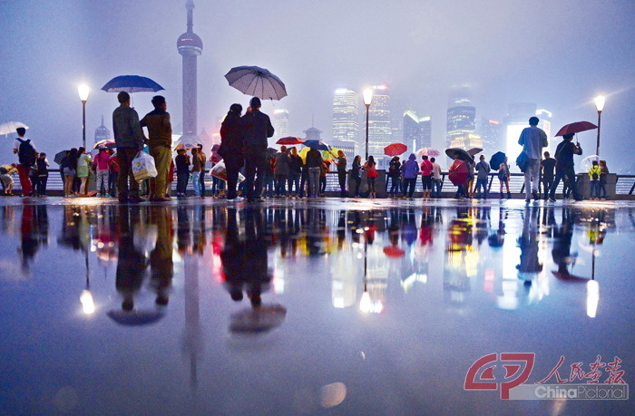 2014年9月22日，游客在上海外滩观光平台上撑伞观赏浦江夜色。 摄影 赖鑫琳