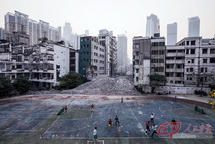 2014年1月14日傍晚时分，广州冼村处于拆迁停滞状态。村民们在一个废弃的小学篮球场上踢足球。 摄影 黎湛均