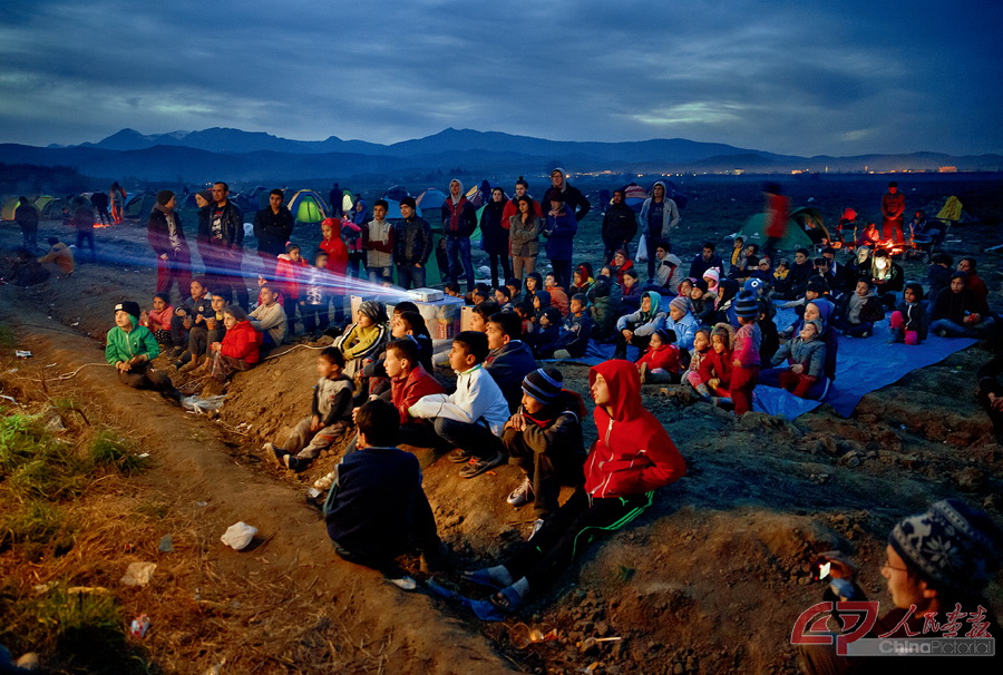露天“电影院” 当地时间2016年3月5日，希腊伊多梅尼，难民和他们的孩子们坐在地上，将一辆卡车的车厢当作银幕，用投影机观看卡通电影。随着巴尔干国家纷纷关闭边境，有越来越多难民被迫滞留希腊北部边境。IC