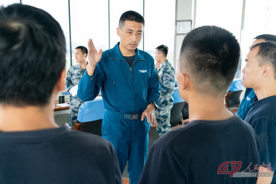 空军“金头盔”飞行员、某旅旅长王永同与训练归来的飞行员们反复琢磨训练情况。.jpg
