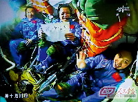 6月12日，神舟十号航天员举起写着“端午节快乐”的字板，通过摄像机镜头送出问候。（摄于北京航天飞行控制中心大屏幕）。 新华社 供图