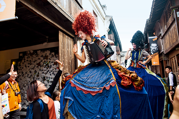 乌镇戏剧节，加拿大美丽贝特剧团的两位女郎踩着高跷，一人演奏手风琴，一人负责带动气氛，一边演奏一边歌唱。-摄影-秦斌.png