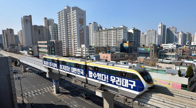 3月23日,在韩国大邱,一辆车身印有"加油"字样的地铁列车从市区驶过.